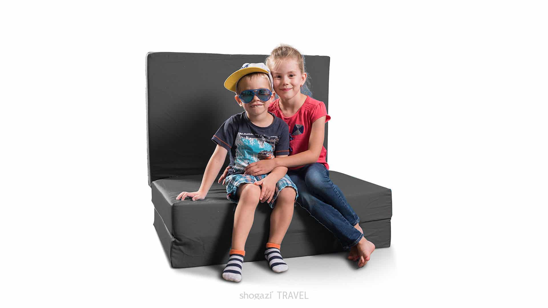 Auf einer Klappmatratze in anthrazit sitzen zwei Kinder